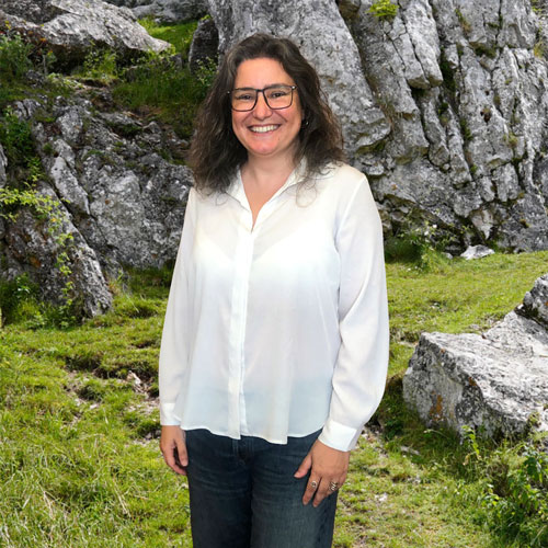 Close-up of Celia Martins, outdoors, in a white shirt, smiling.