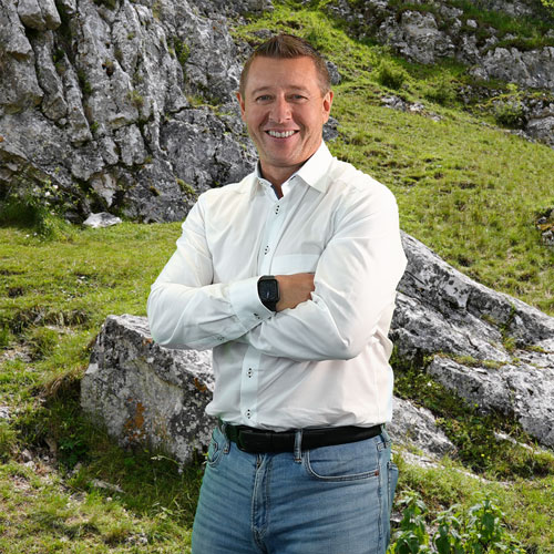 Close-up of Christian Stenske, outdoors, in a white shirt, smiling.