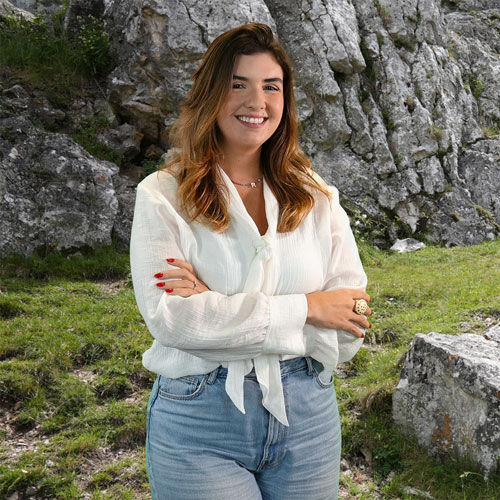 Close-up of Renata Ferreira, outdoors, in a white shirt, smiling.