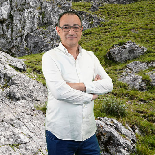 Close-up of Ahmet Sahin, outdoors, in a white shirt, smiling.