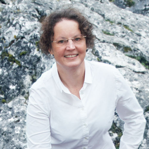 Close-up of Andrea Schüssele, outdoors, in a white shirt, smiling.