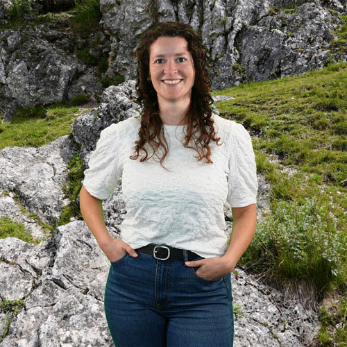 Close-up of Brit Gründlich, outdoors, in a white shirt, smiling.