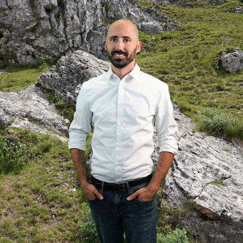 Close-up of Dillon Abraham, outdoors, in a white shirt, smiling.