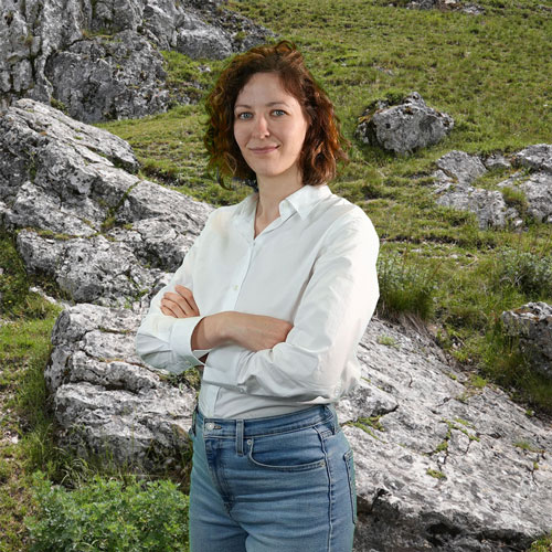 Close-up of Dr. Elise Schüler, outdoors, in a white shirt, smiling.