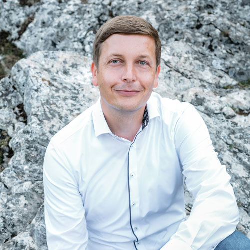 Close-up of Harald Keller, outdoors, in a white shirt, smiling.