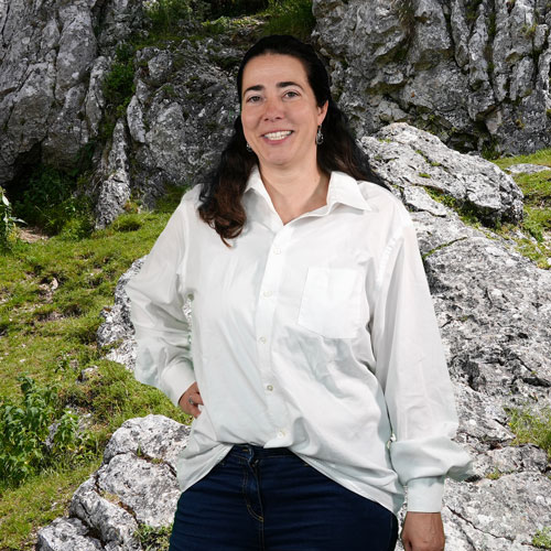 Close-up of Heike Gloede, outdoors, in a white shirt, smiling.