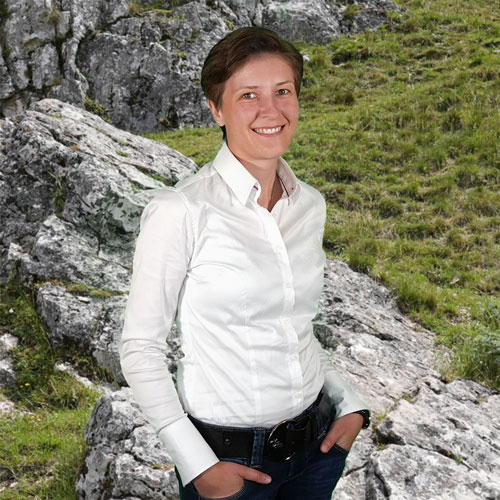 Close-up of Jasmin Ritz, outdoors, in a white shirt, smiling.