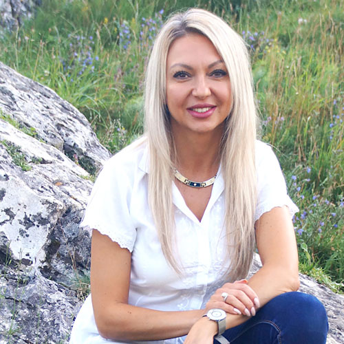 Close-up of Juliana Gavrilenko, outdoors, in a white shirt, smiling.