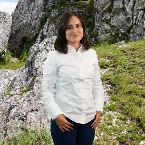 Close-up of Marina Costa, outdoors, in a white shirt, smiling.