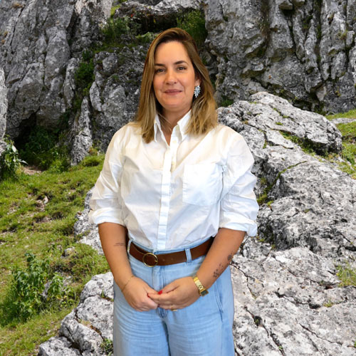 Close-up of Raquel Correia, outdoors, in a white shirt, smiling.