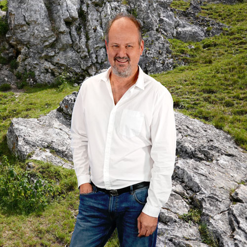 Close-up of Uwe Rosin, outdoors, in a white shirt, smiling.