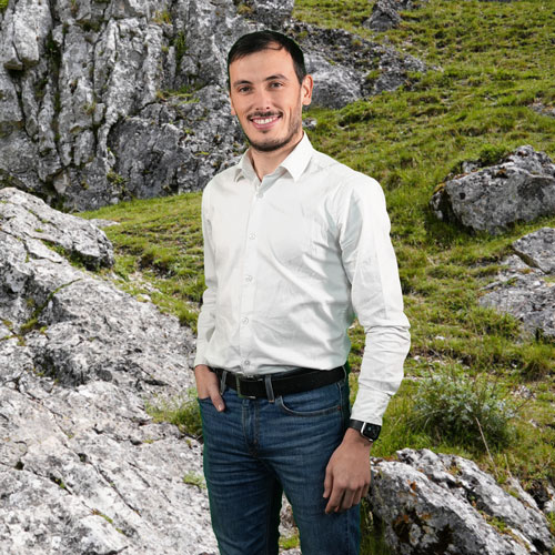 Close-up of Andre Braga, outdoors, in a white shirt, smiling.