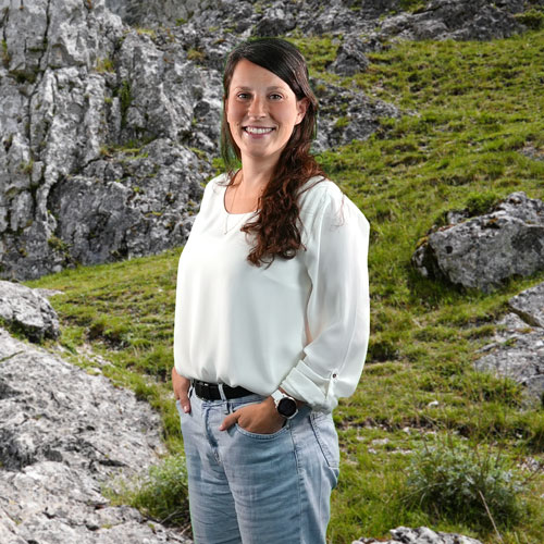 Close-up of Christiane Pfeffer, outdoors, in a white shirt, smiling.