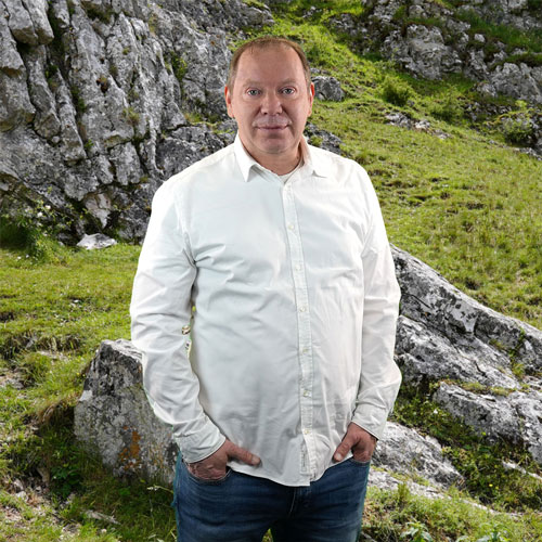 Close-up of Henning Neubauer, outdoors, in a white shirt, smiling.