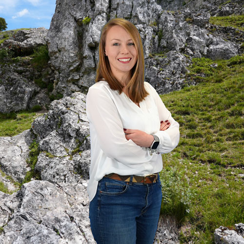 Close-up of Ivana Klincharska, outdoors, in a white shirt, smiling.