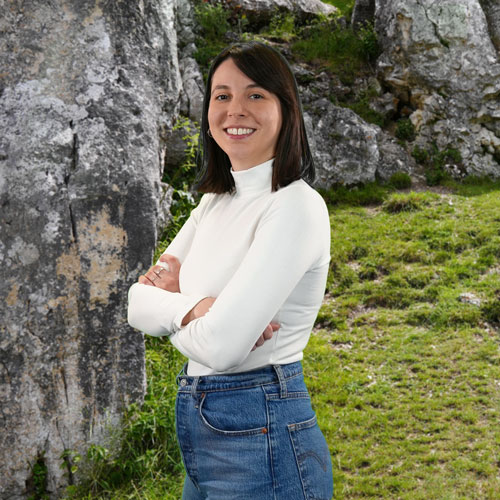 Close-up of Karla Giacomelli Ribas, outdoors, in a white shirt, smiling.