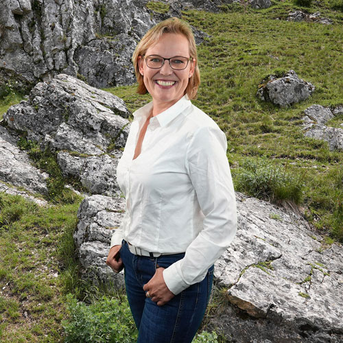 Close-up of Laura Leupolt, outdoors, in a white shirt, smiling.