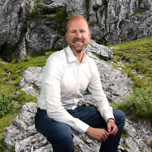 Close-up of Dr. Markus Lutz, outdoors, in a white shirt, smiling.