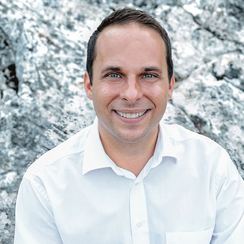 Close-up of Nikolai Wiedemann, outdoors, in a white shirt, smiling.