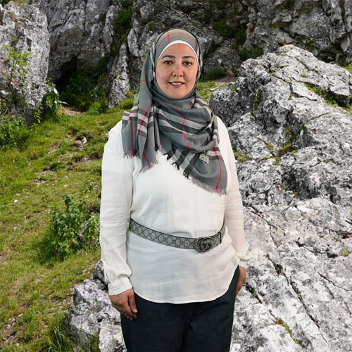 Close-up of Racha Helal, outdoors, in a white shirt, smiling.