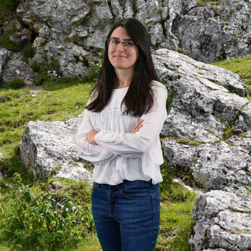 Close-up of Dr. Sílvia Rodrigues, outdoors, in a white shirt, smiling.