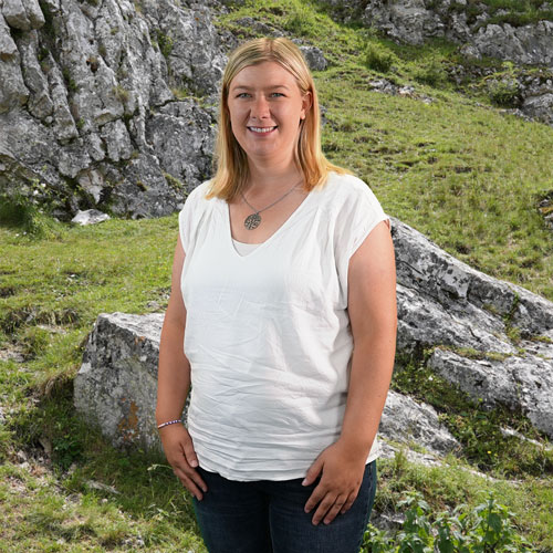 Close-up of Dr. Jennifer Eymael, outdoors, in a white shirt, smiling.