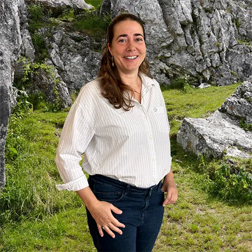 Close-up of Heike Gloede, outdoors, in a white shirt, smiling.
