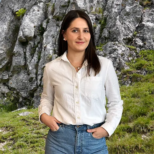 Close-up of Iva Gjolli, outdoors, in a white shirt, smiling.