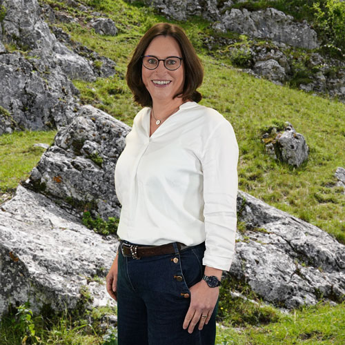 Close-up of Dr. Juliane Meutsch, outdoors, in a white shirt, smiling.