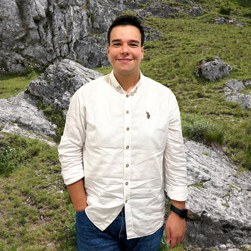 Close-up of Yunus Kaydan, outdoors, in a white shirt, smiling.